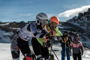 Sehbehinderte Skifahrer werden von Begleitläufern die Piste hinunter geführt oder geleitet
